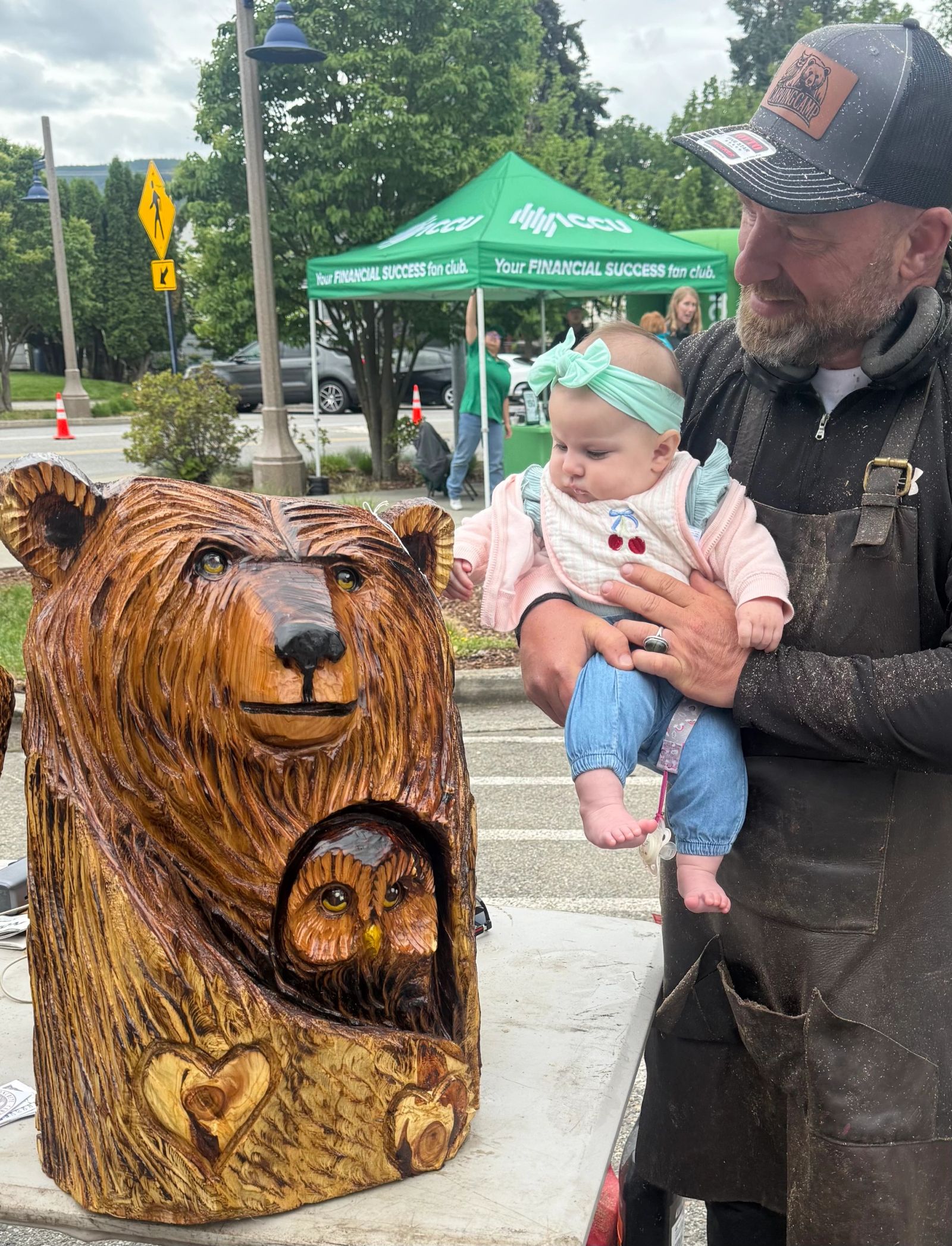 Spokane chainsaw artist Aaron Chavez beside a custom bear and owl carving